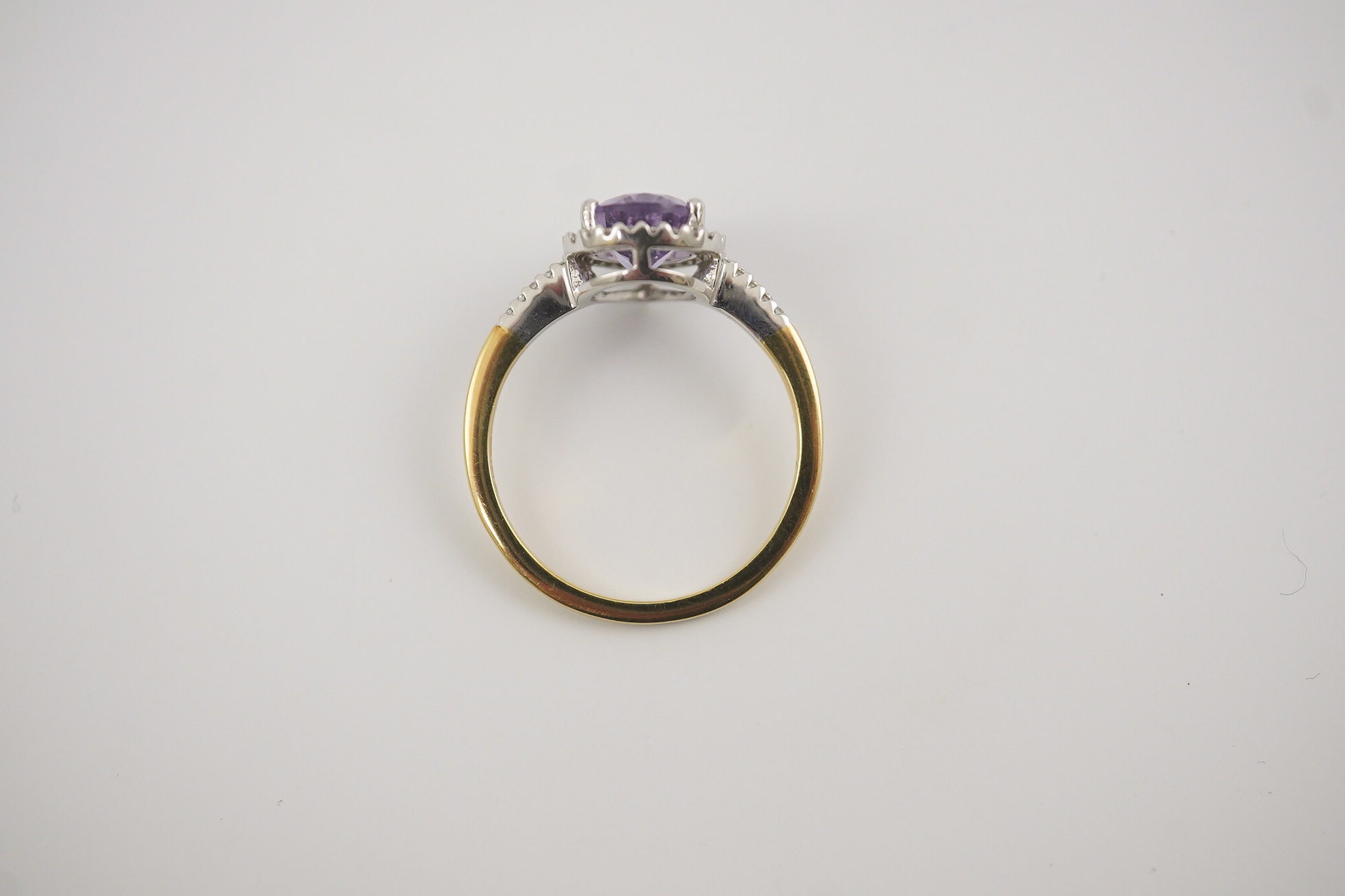 A modern 18ct gold and single stone pear cut amethyst set ring, with diamond chip set border and shoulders, size O, gross weight 3.4 grams. Condition - fair to good